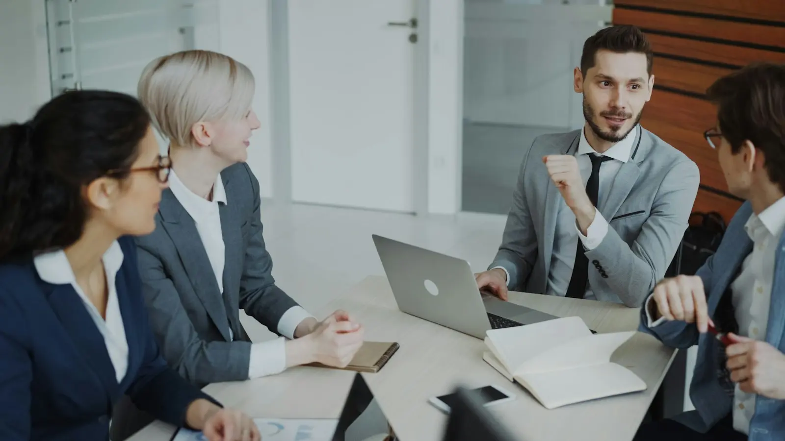 Vier collega's in overleg aan een vergadertafel met laptops