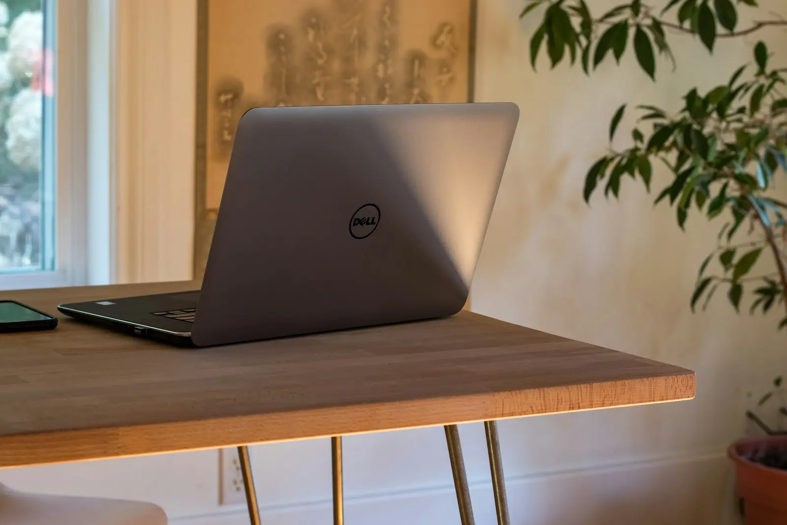 Laptop op een houten bureau bij het raam