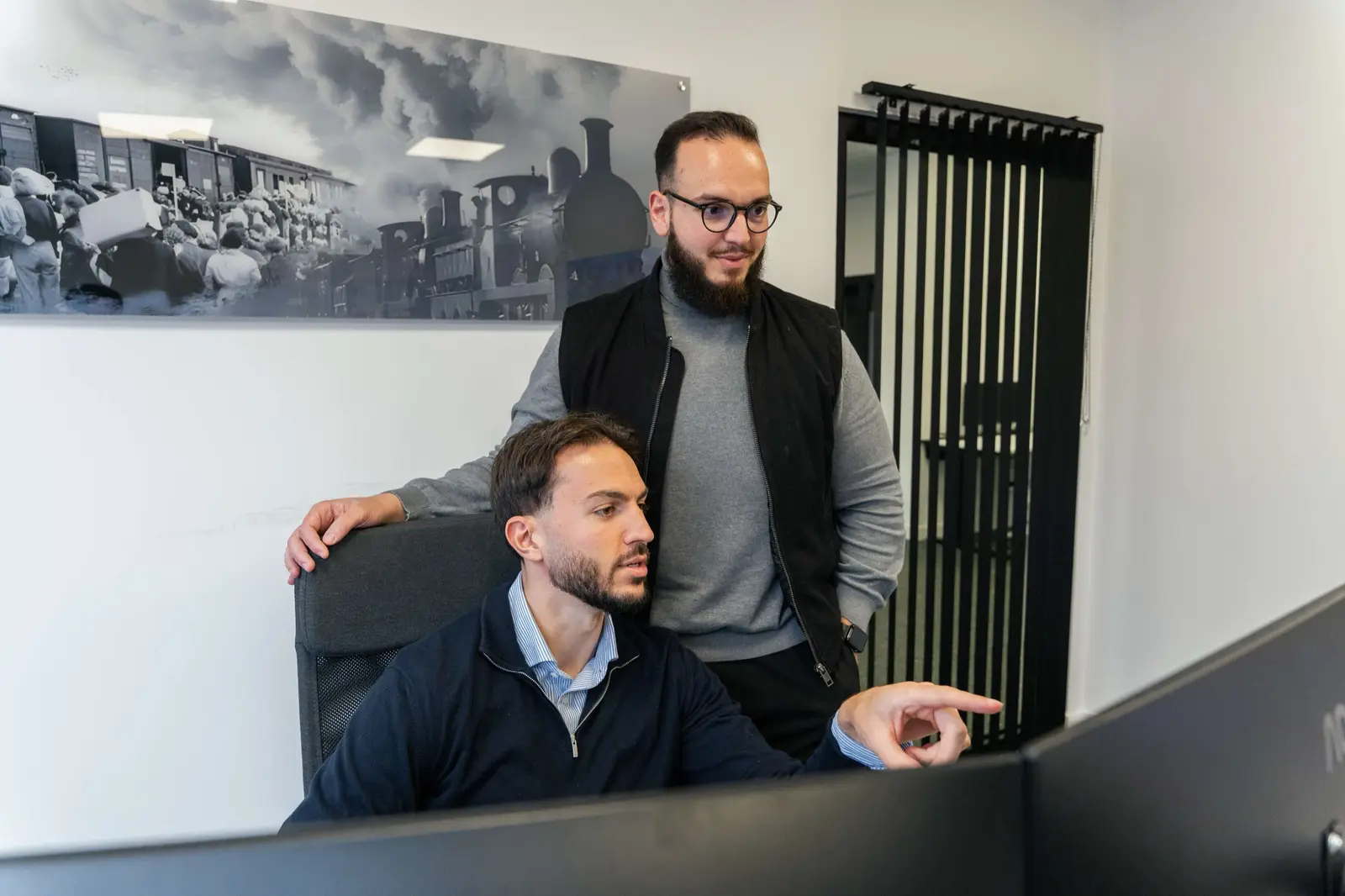 Twee MINIMA-collega's bekijken samen een scherm op kantoor