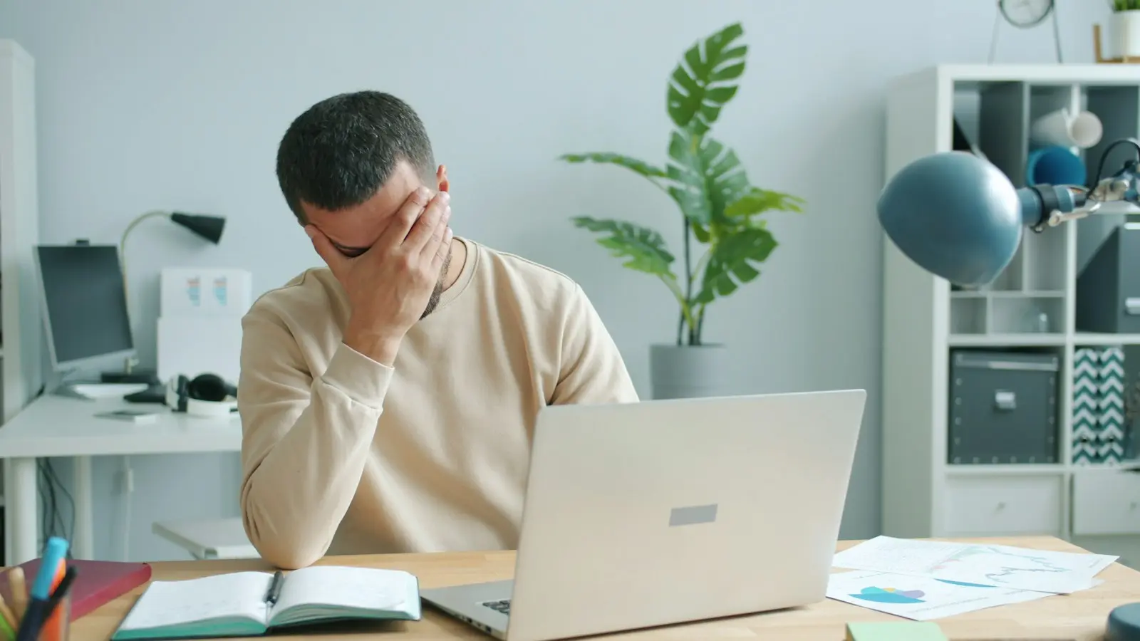 Medewerker met de hand voor het gezicht achter een laptop