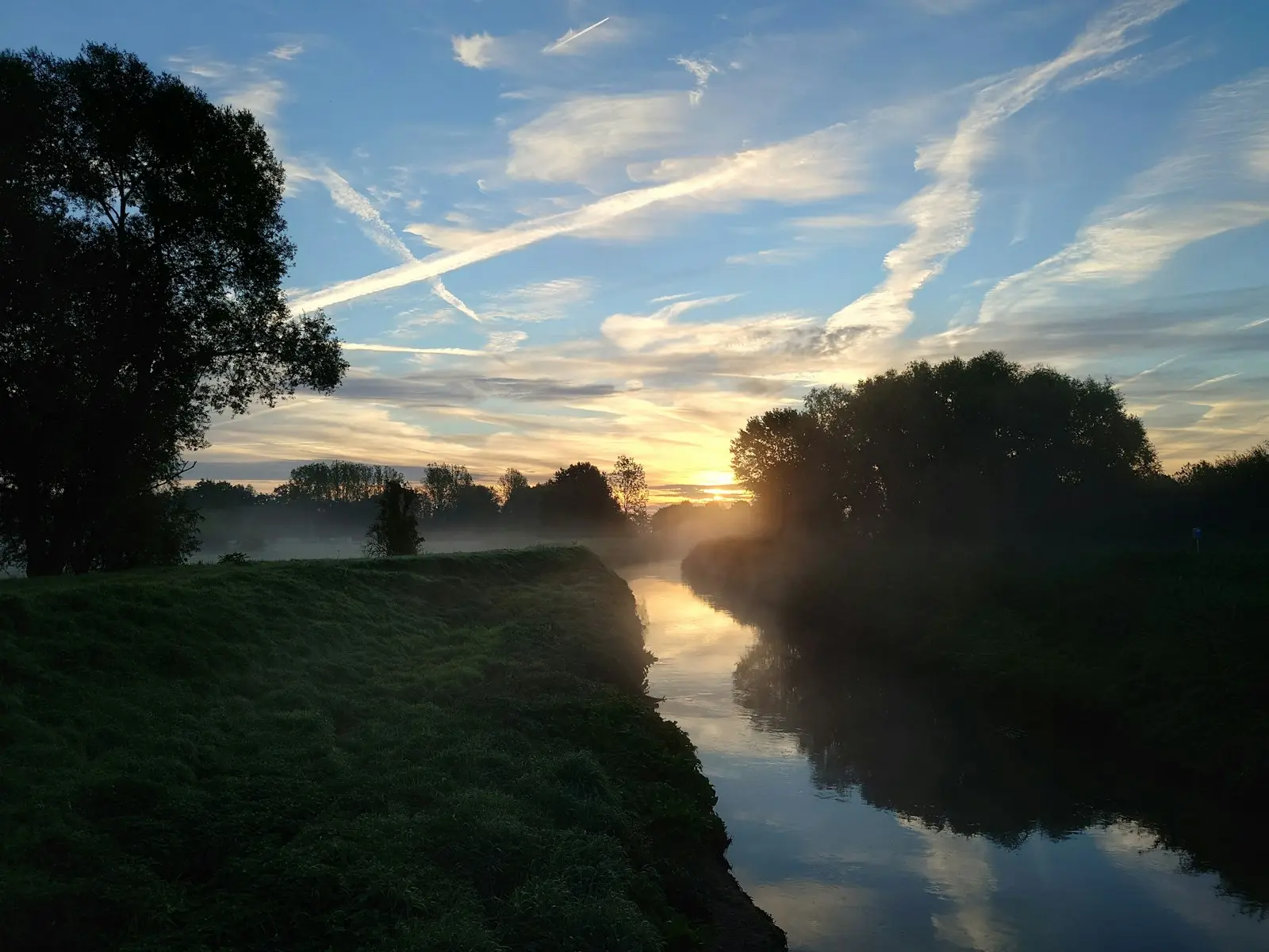 Rivier met groene oevers bij zonsopgang in Halen